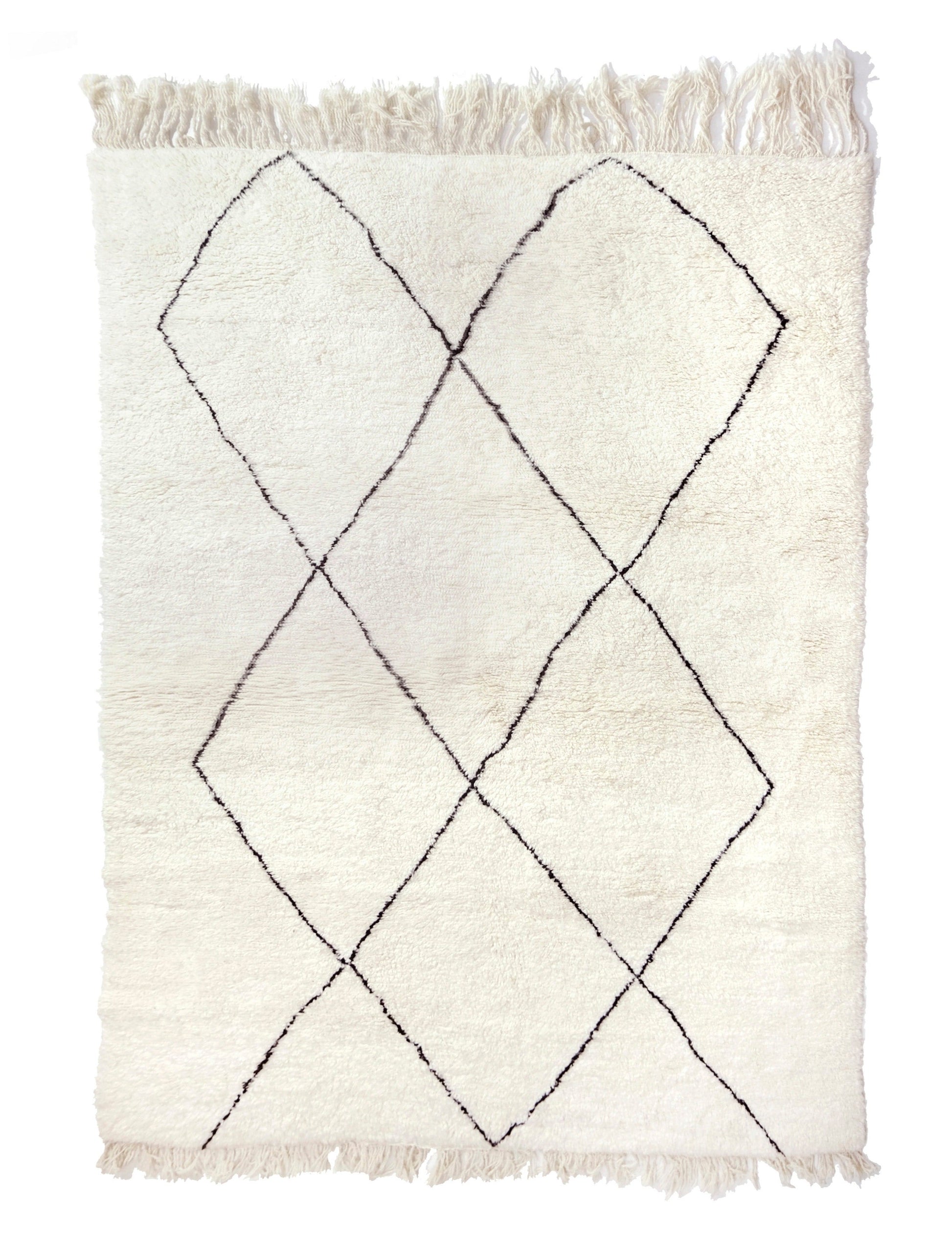 Plush cream wool Moroccan Beni Ourain rug with thin, black hand-drawn diamond lozenge lines and fringe on the top and bottom, shown on a white background.

