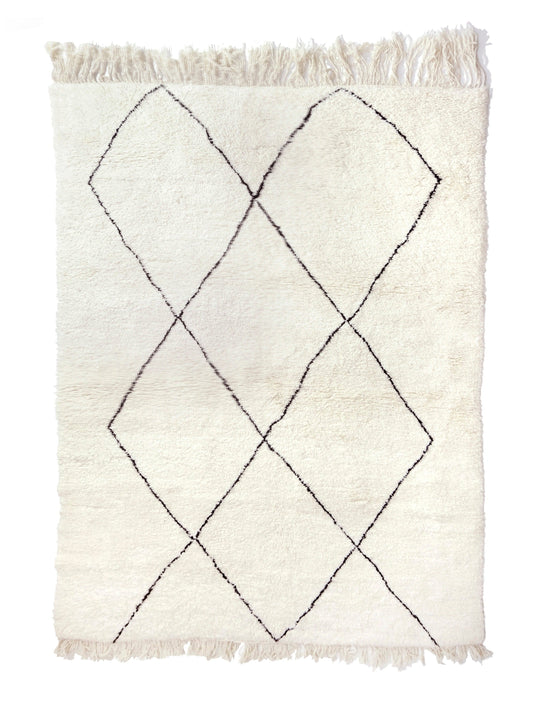 Plush cream wool Moroccan Beni Ourain rug with thin, black hand-drawn diamond lozenge lines and fringe on the top and bottom, shown on a white background.

