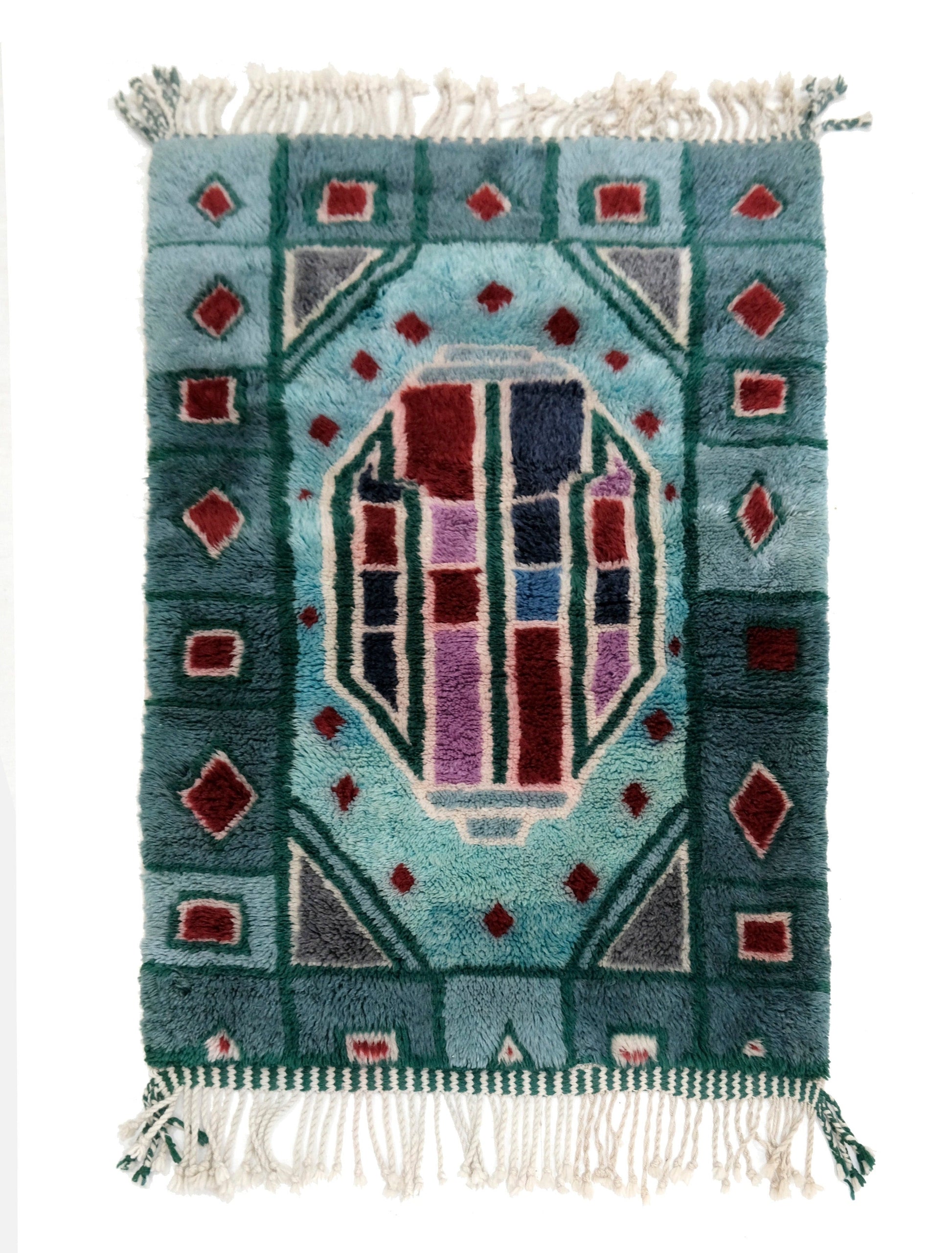 Handwoven plush wool Moroccan rug featuring a teal blue border and a central stained-glass style geometric medallion in burgundy, navy, and lavender, with a chunky cream fringe on a white background
