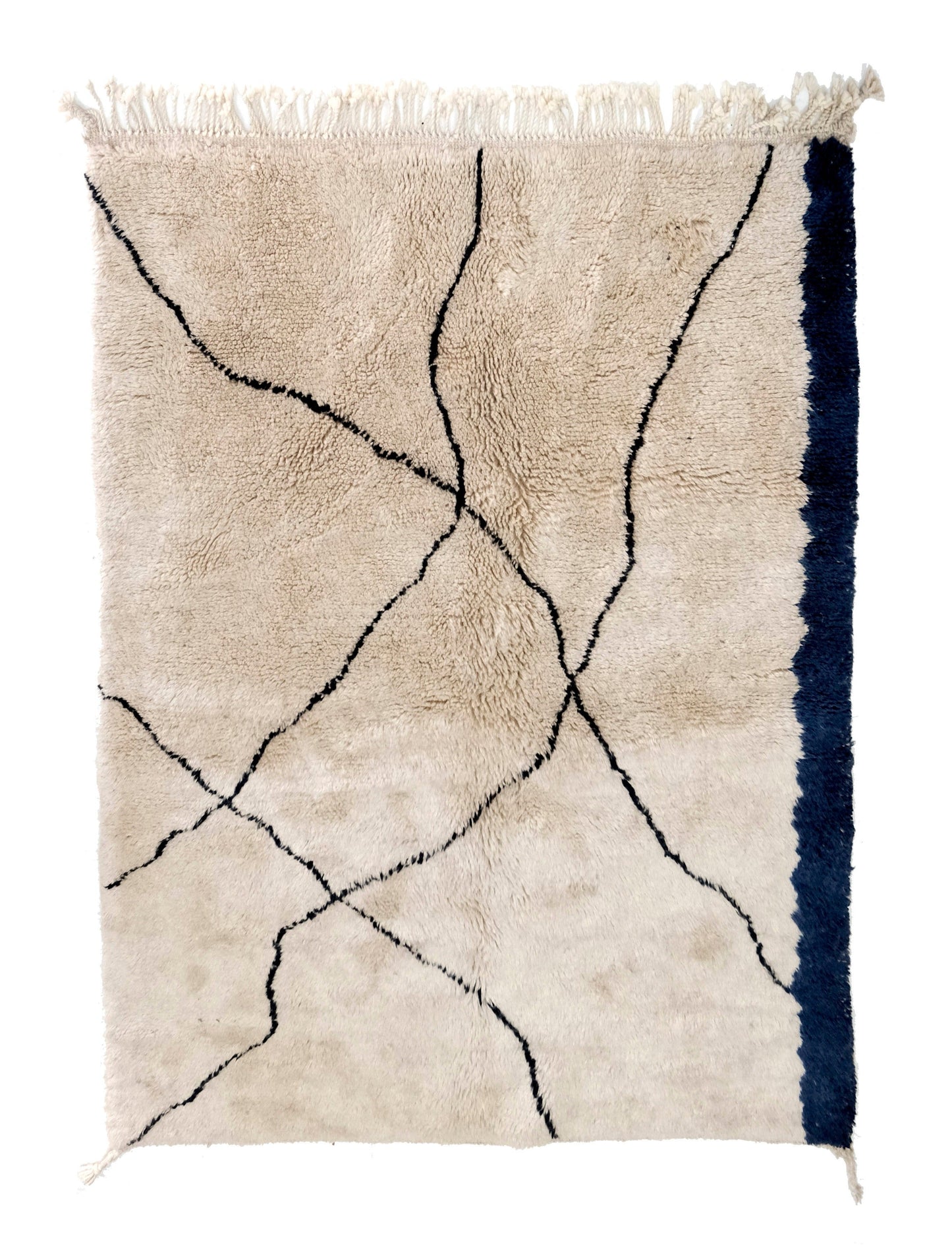 Plush cream wool Moroccan rug with organic wavy black intersecting lines and a bold asymmetrical navy blue stripe along the right edge, finished with a top cream fringe, displayed on a white background.