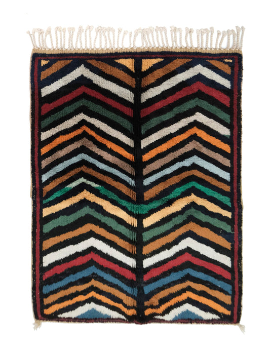 Plush handwoven Moroccan Azilal wool rug with colorful chevron zigzag stripes in pink, orange, navy, and mint, featuring a central dark navy spine with horizontal notches, finished with top fringe and small corner ties, displayed on a white background.


