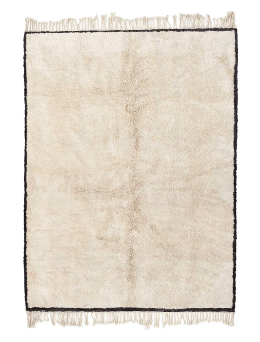 Plush cream wool rug featuring a thin black border framing the entire perimeter, a subtle vertical central seam, and knotted fringed edges on both the top and bottom, displayed on a white background.