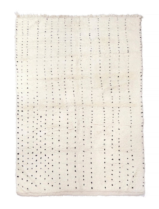 Plush cream wool rug featuring vertical dashed lines made of hand-knotted black dots and a short fringe along the top edge, displayed on a white background.

