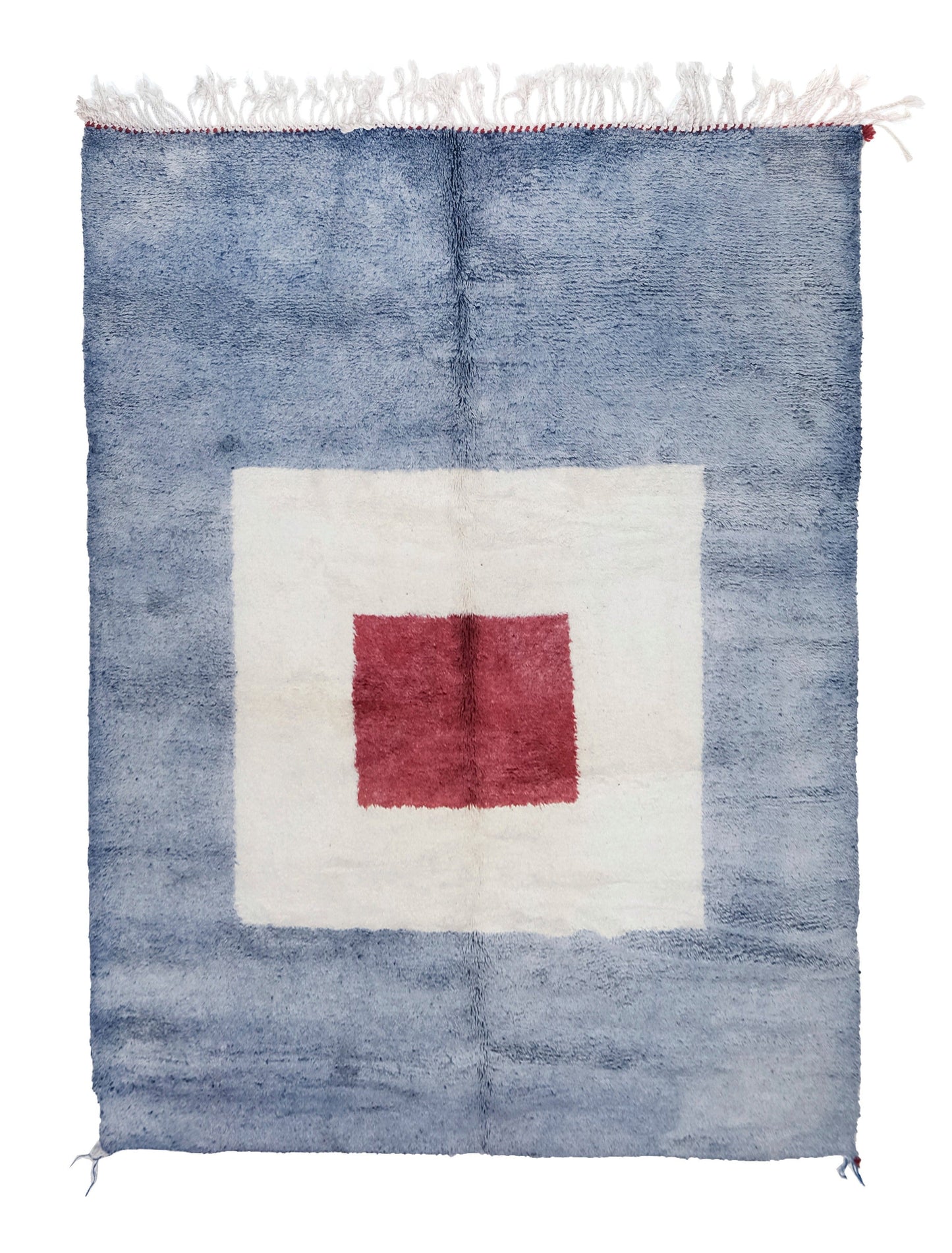A plush handwoven Moroccan rug with a mottled light blue background, featuring a large white square in the center with a smaller red square inside it, finished with white fringe and red corner accents on the top and bottom edges.

