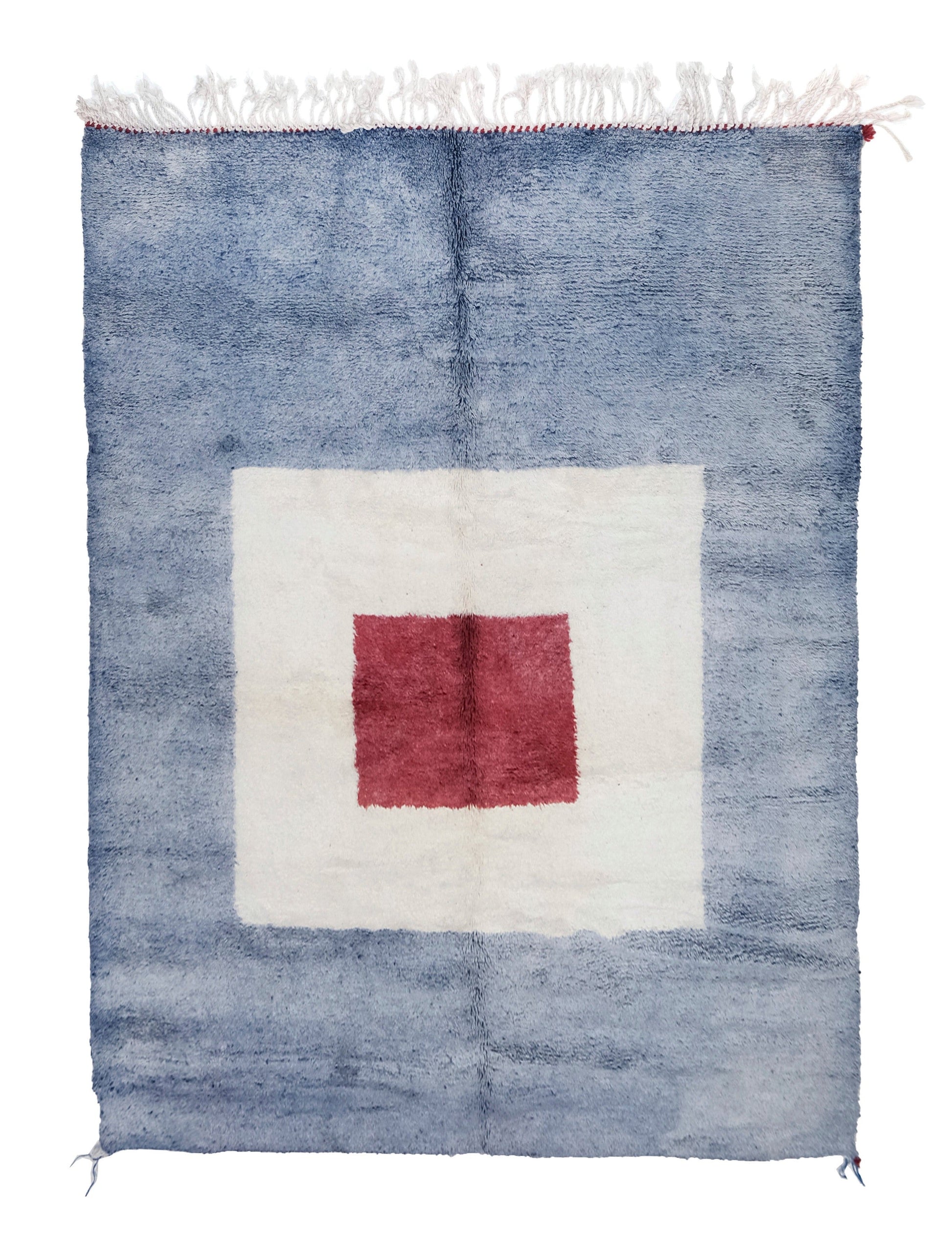 A plush handwoven Moroccan rug with a mottled light blue background, featuring a large white square in the center with a smaller red square inside it, finished with white fringe and red corner accents on the top and bottom edges.

