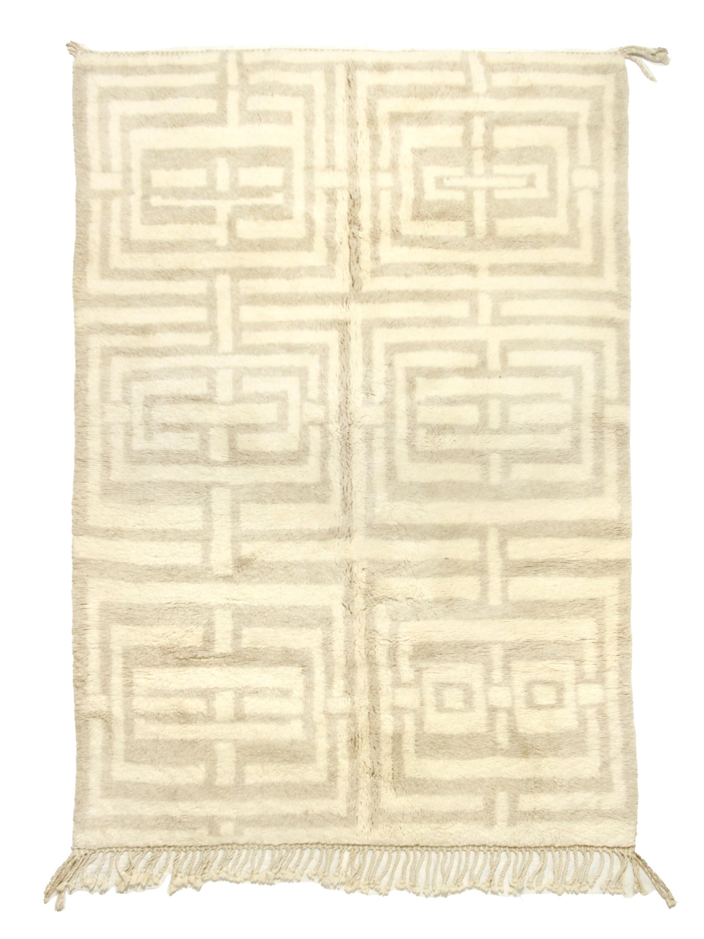 
A cream-colored handwoven Moroccan shag rug featuring a large geometric beige maze or Greek key pattern arranged in a grid of six blocks, finished with fringe on the bottom edge and corner ties at the top.


